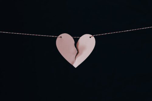 A pink paper heart on a string tearing in half.
